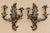 Pair of vintage Chinoiserie-style gilt metal candle wall sconces with colorful figural centers, sculptural foliage, and...