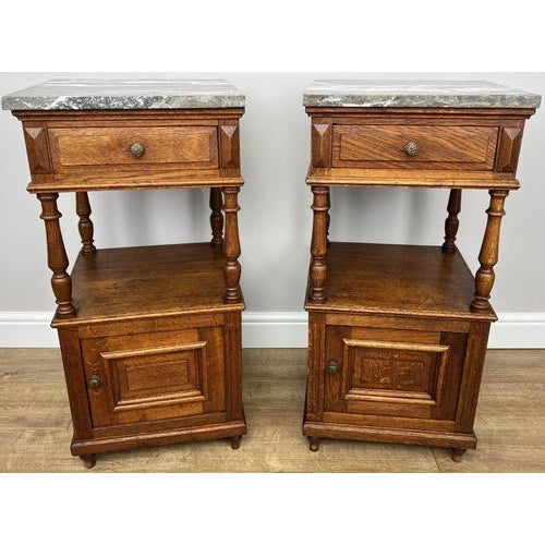 A charming pair of Antique French bedside tables featuring striking marble tops and beautifully aged oak, offering both...