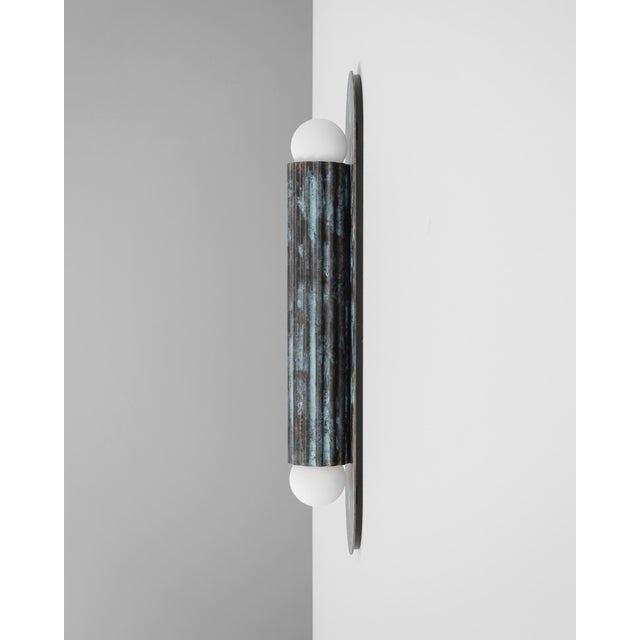 A single fluted cylinder rests on an oval plate, its geometry distilled to pure form. Entirely crafted in solid brass, it...