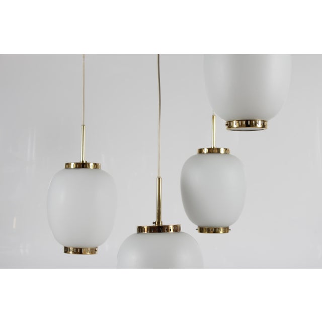 Set of four China pendents made of off-white opaline glass and with brass fittings. The pendants are designed by Danish...