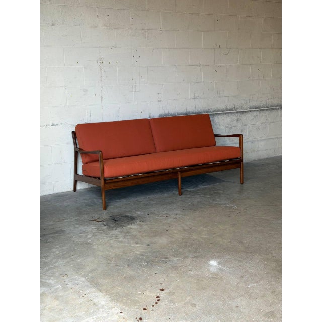 Featuring sculpted wooden armrests and an open spindle back frame, this three-seat sofa showcases architectural lines. In...
