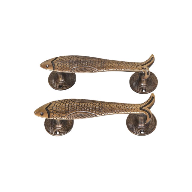 A pair of fish shaped door handles or cabinet pulls made of brass with an antique finish. Cast with delicate scales and...