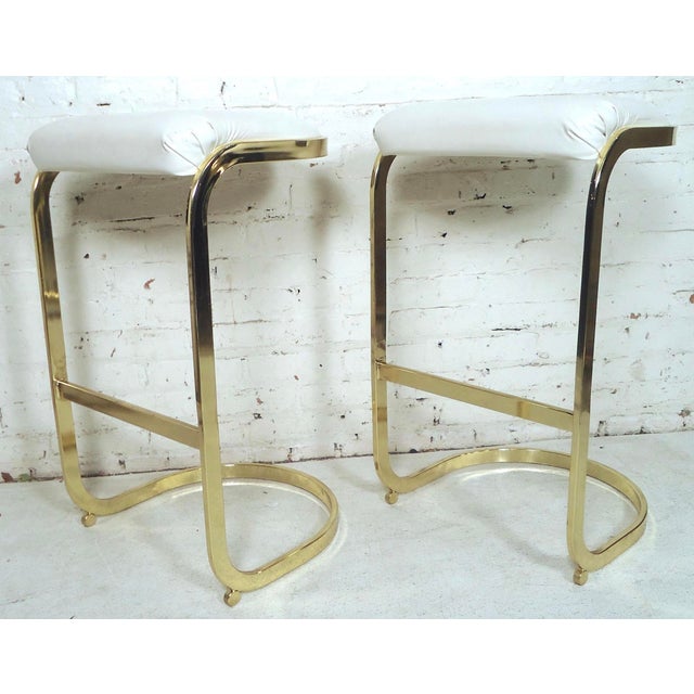 Mid-Century Modern stools with polished brass frame and white seats. (Please confirm item location - NY or NJ - with dealer).