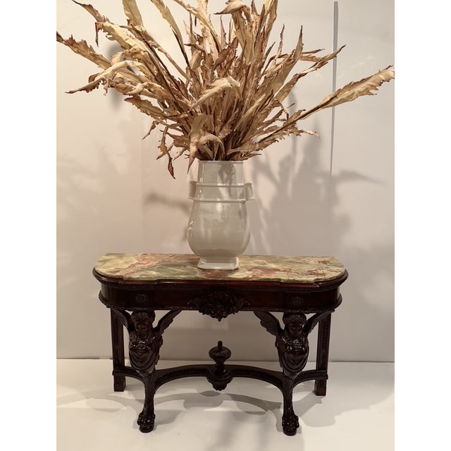 Impressive carved mahogany console table having figural forms and paw feet, topped off palatially with gorgeous curved...