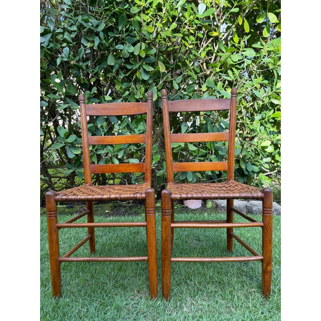 A pair of vintage ladder back dining chairs featuring warm wood frames and handwoven basketweave rattan seats. Clean...