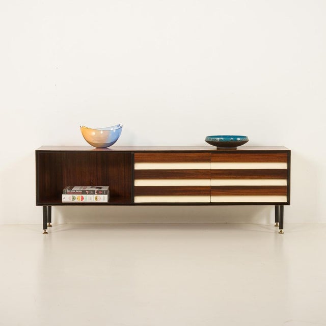 This rare, low Italian rosewood sideboard embodies 1960s mid-century design with contrasts and architectural elegance. The...