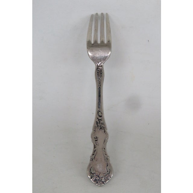 This lovely Dinner Fork is made out of metal and silver plated. It features a lovely floral scrollwork motif on the handle...