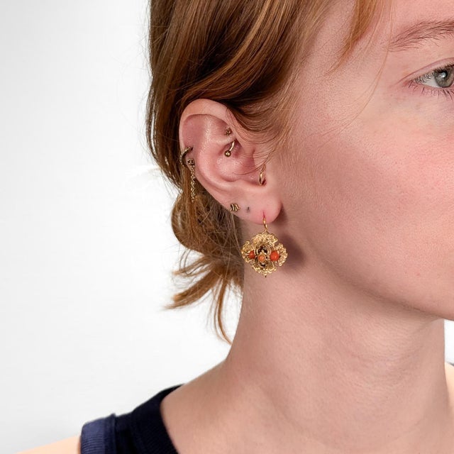 A fine pair of Victorian earrings. In 14k yellow gold. With salmon or red colored coral elements set under a curved mount...