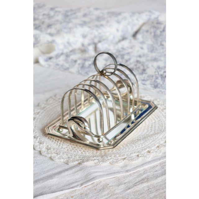 Elegant antique silver-plated toast rack, adorned with two swans at the ends and accompanied by a glass tray. Composed of...