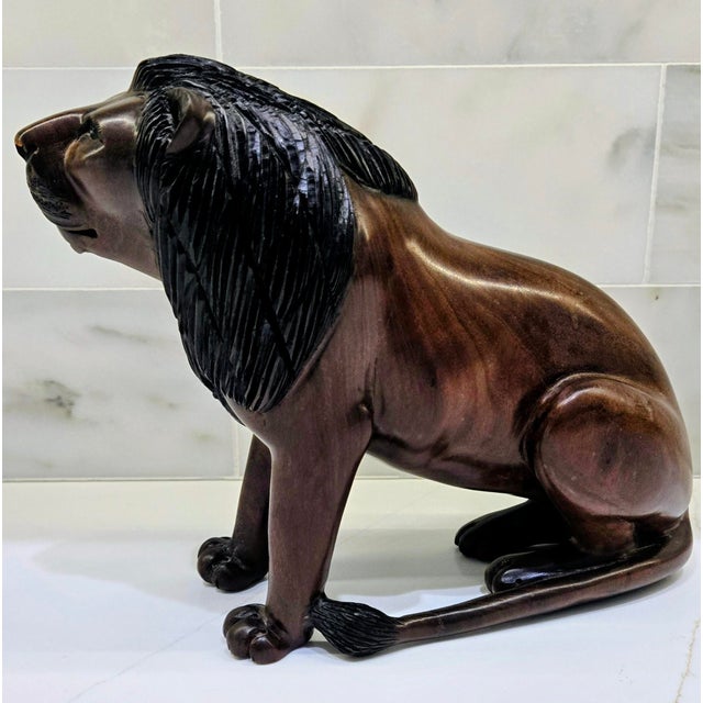 Bring bold African folk art into your space with this striking hand-carved hardwood lion sculpture, signed “Nguma” on the...