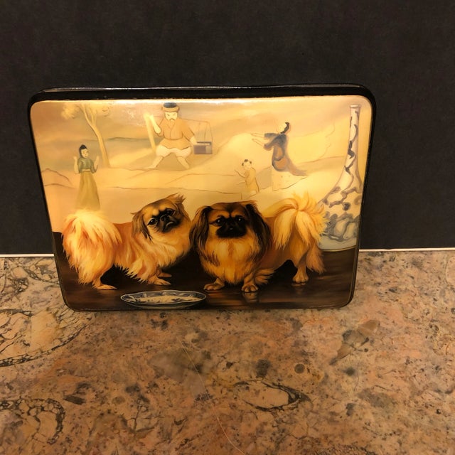 Fine hand painted Russian lacquer hinged box. A pair of pekingese dogs in front of an ancient oriental scene and among...