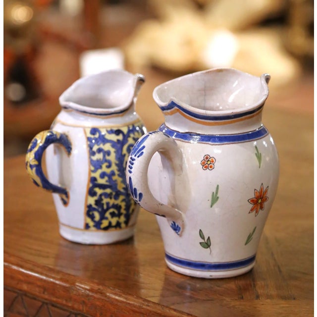 Bring a touch of rustic Breton charm to your collection with this delightful pair of Quimper faience jugs, crafted in...