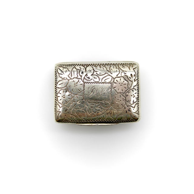 This sterling silver vinaigrette dates to the William IV era. It is engraved with a floral design and a sprigged script...