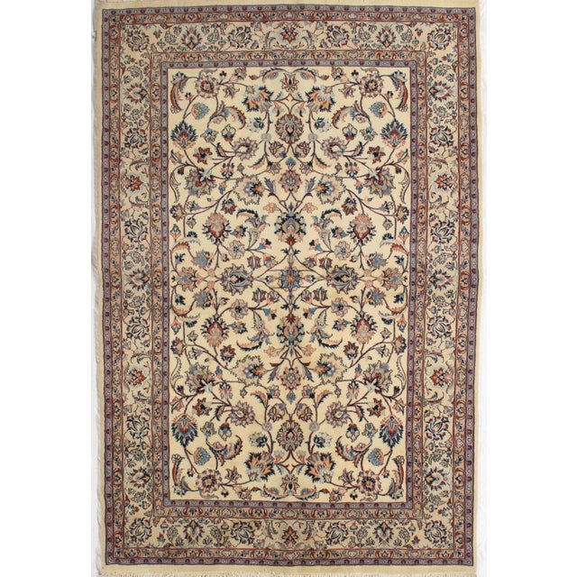 Antique hand-knotted Persian Mashad wool rug with an ivory field featuring an allover floral pattern of scrolling vines...