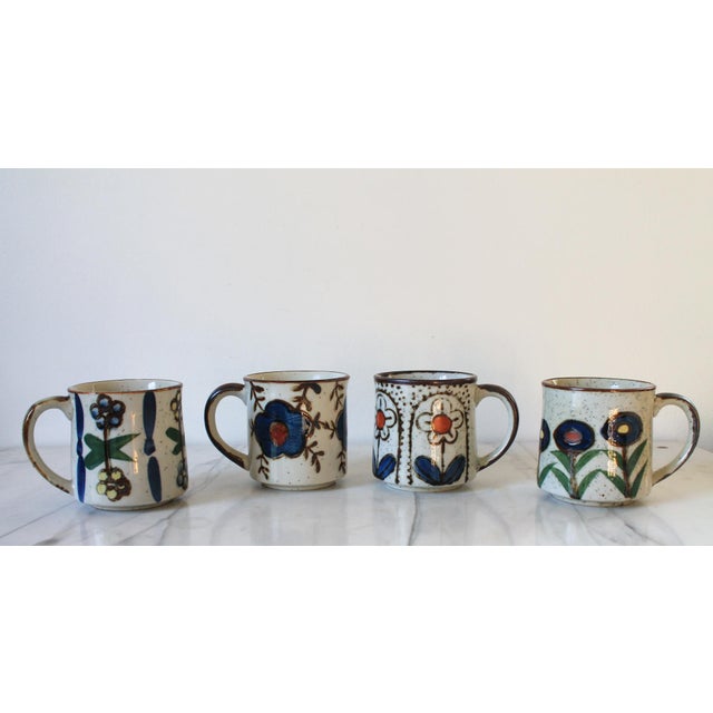 Set of four vintage mid-century speckled cream stoneware coffee mugs featuring hand-painted folk floral and botanical...
