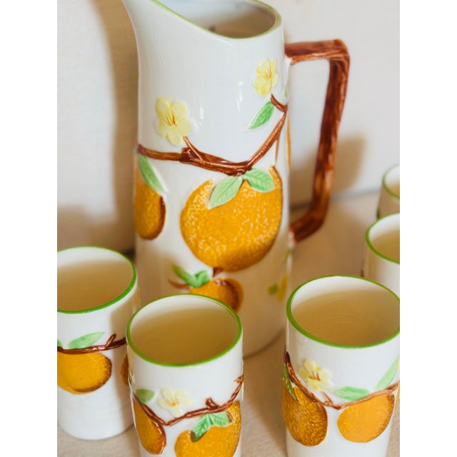 Charming vintage ceramic lemonade or juice set featuring a tall pitcher and five matching tumblers adorned with raised...