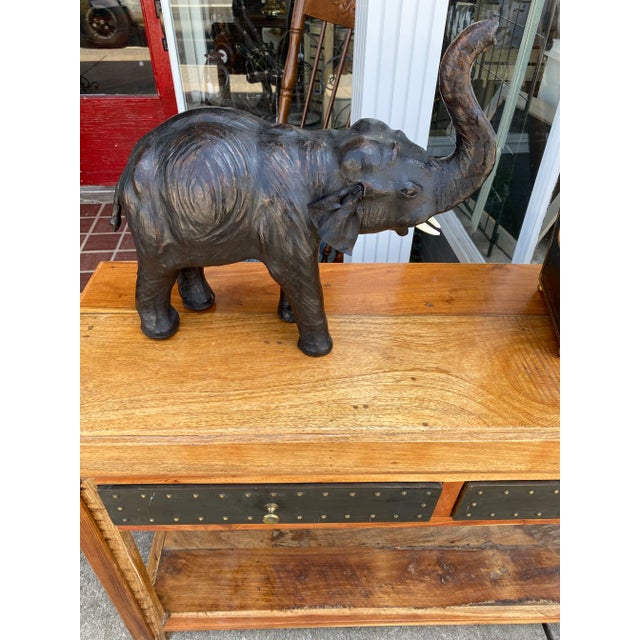 Leather Elephant in a rich black and brown color with white tusks and trunk up right . Flappy leather ears as well with...