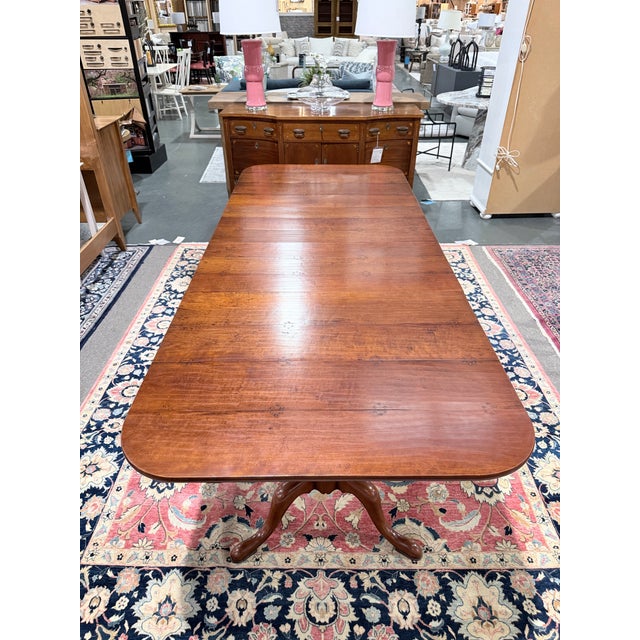 Substantial solid wood dining table featuring a traditional double pedestal base with gracefully curved tripod legs. The...