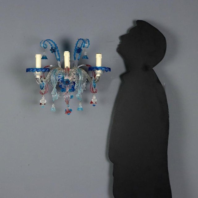 Pair of colored blown glass wall sconces. Four lights, a central one surrounded by curled leaves and three supported by...