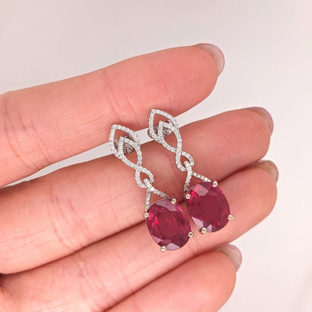 These beautiful dangle earrings feature a pair of 8.19 carat weight oval Ruby gemstones with natural earth mined diamonds...