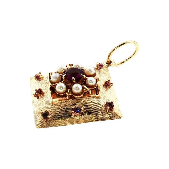 A mid-century 14k gold charm featuring a central round purple amethyst surrounded by white cultured pearls. The design is...