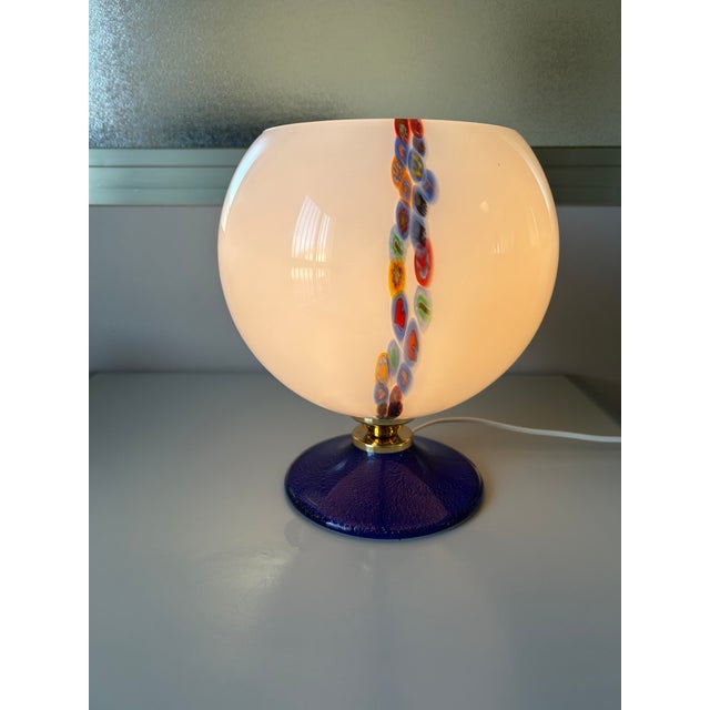 White spherical Murano glass lamp with multicolored murrine fused along the glass's length to create a colorful and...