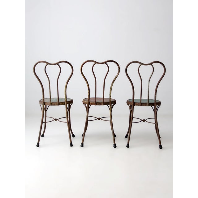 A set of three early 20th century iron bistro chairs with a flowing Art Nouveau line. The backrests form continuous,...