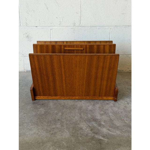 This freestanding magazine rack features an angled profile with dual storage compartments. A raised central divider...