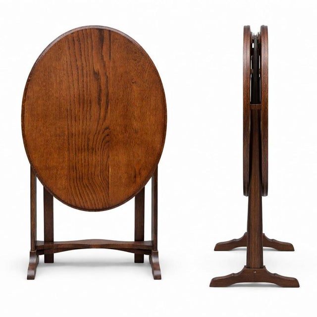 A charming Arts & Crafts oak folding wine table, featuring a beautifully grained oval top and an elegant folding frame....