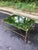 A refined coffee table by featuring an elegant antiqued brass-finished metal frame paired with a mirrored glass top and...