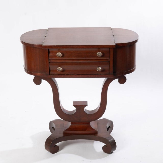 Empire revival lyre form mahogany sewing stand with 2 drawers and lift top side compartments.