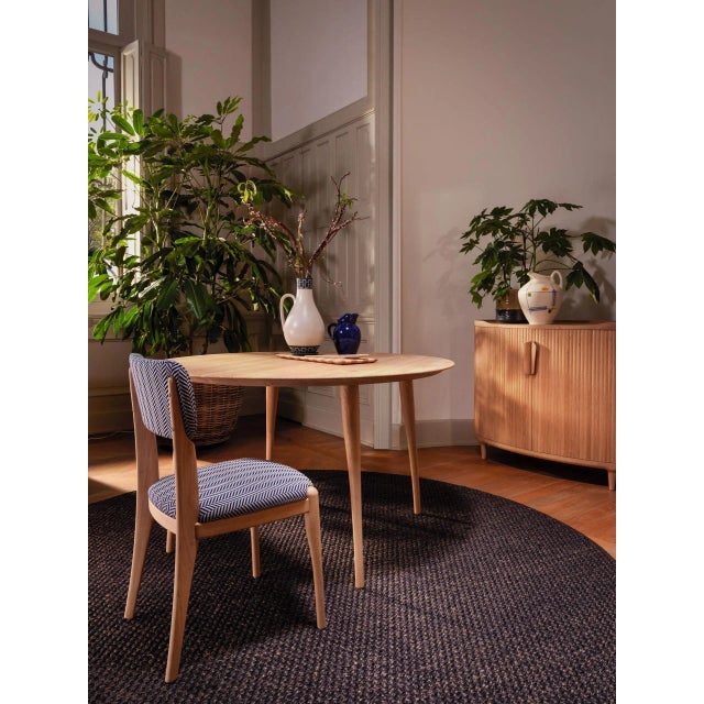 A round dining table (diameter 130cm) crafted from solid wood with powder coated fixtures and featuring an edged profle....