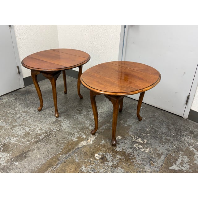Design Plus Gallery presents a Pair of Queen Anne Style Drop-Leaf Side Tables. The set offers round drop-leaf tops with...