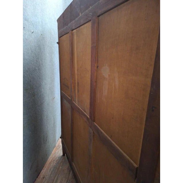 A solid mahogany Empire-style wardrobe with three doors, including a central glazed door fitted with its original wire...