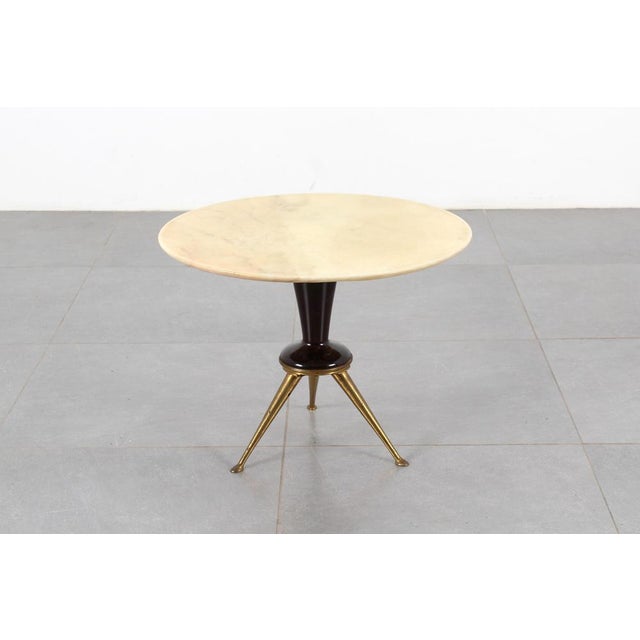 Elegant coffee table with a circular light marble top and a central wooden stand with three brass legs. Attributable to...