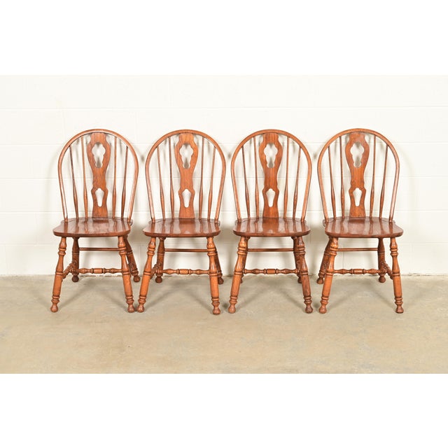 A gorgeous set of four American Colonial style solid oak spindle back Windsor dining chairs In the manner of Ethan Allen...