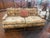 Charming vintage sofa featuring a classic English-inspired silhouette with carved wood detailing and a warm floral...