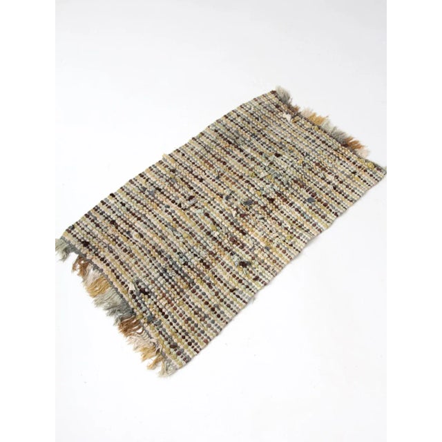 Vintage rag rug with a woven farmhouse look in rich tones of stone, sea-foam, gold, brown, and cream. The subtle mix of...