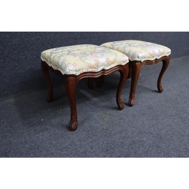 Pair of Henredon footstools with carved cherry frames and cabriole legs. Shaped aprons with carved detailing at the feet....
