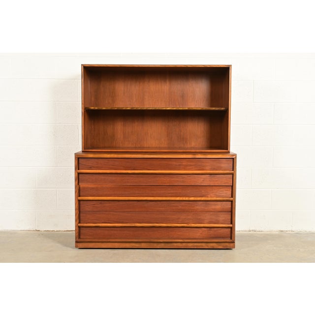 An exceptional Mid-Century Modern sculpted walnut three-drawer dresser or server with bookcase hutch top By T.H. Robsjohn-...