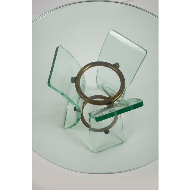 Glass coffee table, with brass structure, thick glass top with three curved glass legs shaped like the grindstone....