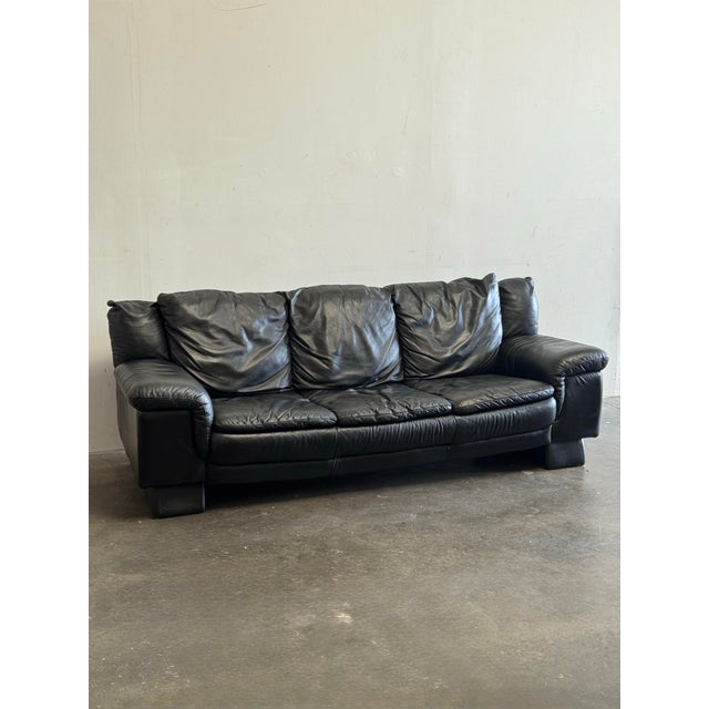 Black leather sofa made in Italy, showcasing the timeless elegance of mid-century modern design. Crafted around the 1980s,...
