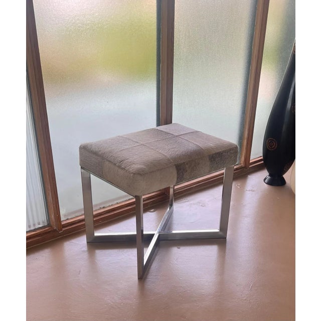 A modernist chrome and cowhide ottoman or stool, probably late 20th century or early 21st century. Likely a mid century...