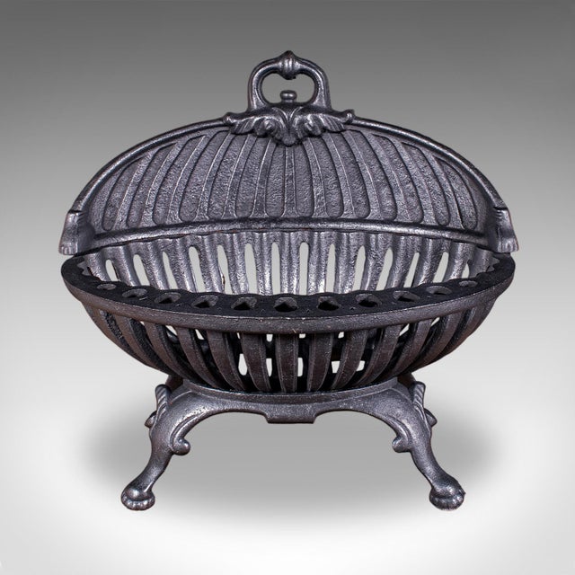 This is an antique Regency revival fire basket. An English, cast iron oval form fireplace grate, dating to the Edwardian...