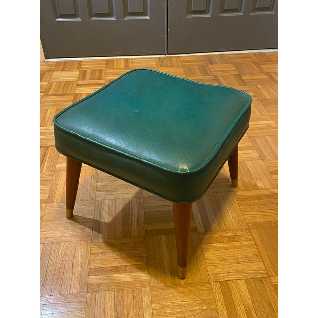 Add a touch of vintage charm to your space with this stylish mid-century modern footstool. Featuring a rich teal vinyl...