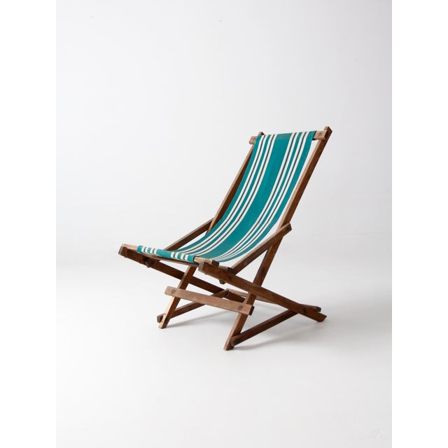This American deck chair, circa 1940, features bold green stripes on its canvas hammock seat. The chair is set on a...