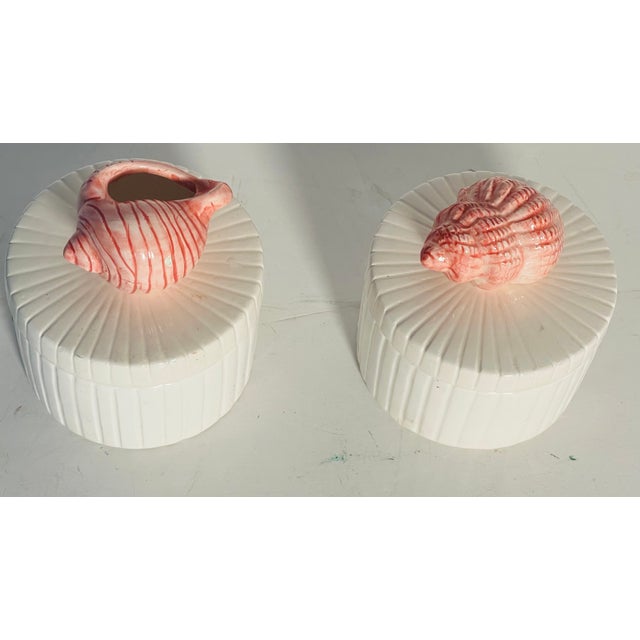 Cute pair of vintage ceramic cylinder boxes with cover and pink sea shells on top.