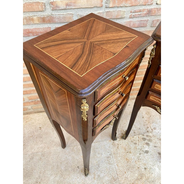 A pair of French Louis XV style nightstands with a marquetry top in TulipWood. The slim body of walnut and tulipwood, each...