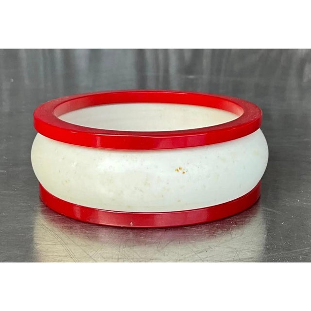 This vintage bangle set pairs a substantial white bangle with two slim red bangles, designed to be worn together for a...