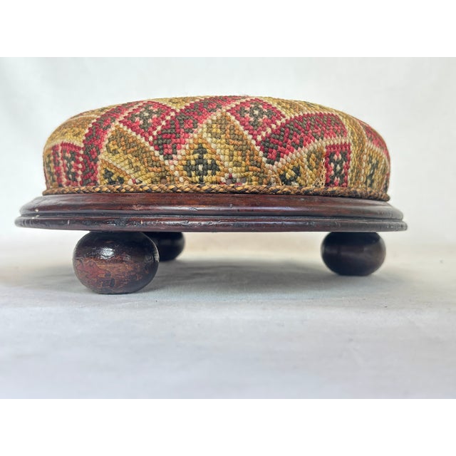 This beautiful needlepoint footstool is in a chevron pattern in red, green, pink, brown, black and gray yarn.